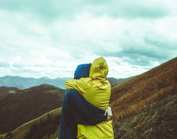 Couple embracing on mountain against sky