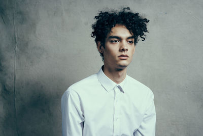 Portrait of young man standing against wall