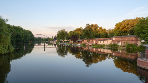 Bridge over river by buildings against sky