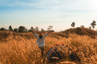 Rear view of man standing by tent on field against sky