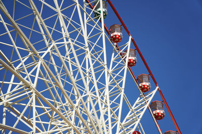 Low angle view of ferris wheel against clear blue sky