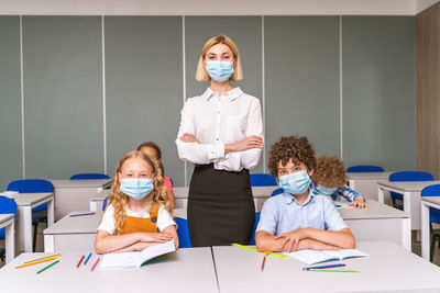 Portrait of teacher wearing mask with student at classroom