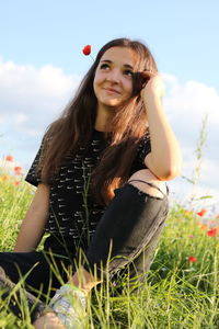 Portrait of beautiful young woman sitting on field