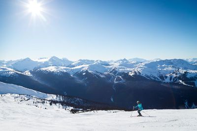 People on snowcapped mountain against blue sky