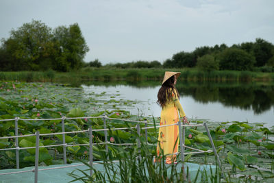 Girl staying near the lotuses lake on the plastic floating pontoon bridge. 