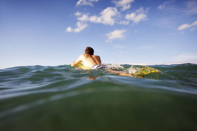 Rear view of man surfboarding in sea