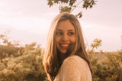 Side view of smiling young woman looking away