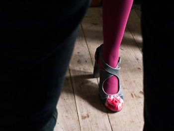 Low section of person wearing pink shoes on hardwood floor