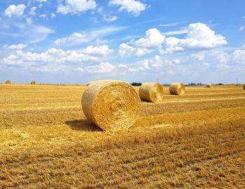 Hay bales on field against sky