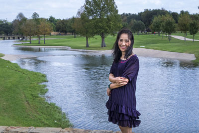 Portrait of smiling senior woman standing by lake