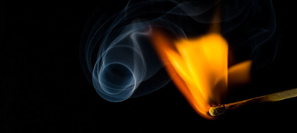 Close-up of lit matchstick against black background