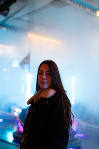 Portrait of young woman looking at illuminated camera