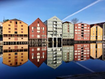 Reflection of buildings in river against blue sky