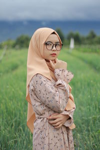 Midsection of woman with umbrella standing on field