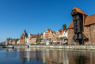 Buildings at waterfront against blue sky