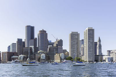 Sea by buildings against clear sky in city