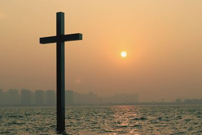 Silhouette cross against sky during sunset