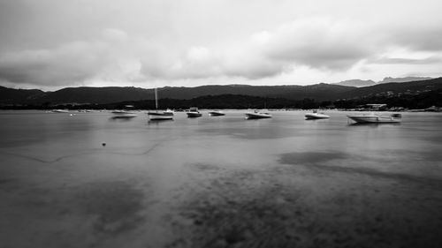 Sailboats in sea against cloudy sky