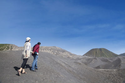 Man with umbrella on mountain against sky