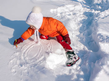 Girl drawing on snowy land