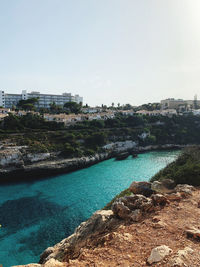 Scenic view of river by buildings against clear sky