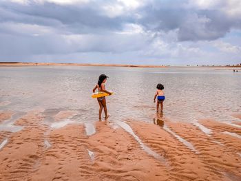 Children playing at beach against sky