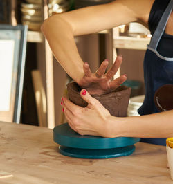 Midsection of woman making earthenware on table