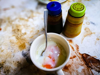 Half boiled eggs with soy sauce and pepper served in a cup on a stained table.