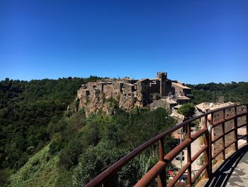 Built structure on landscape against clear blue sky