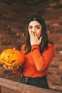 A beautiful girl with dark hair with makeup for the celebration of halloween holds a pumpkin 