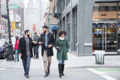 Business people talking while crossing road in city