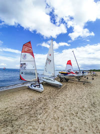 Sailboats moored on beach against sky