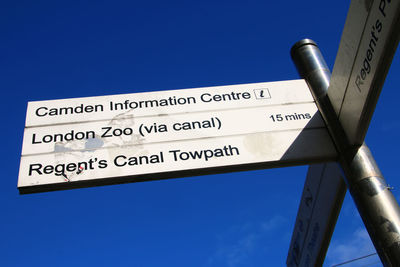 Low angle view of information sign against clear blue sky