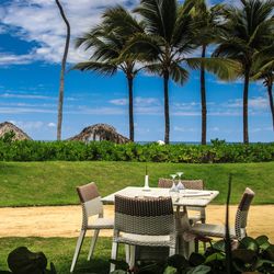 Chairs and table by palm trees against sky