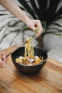 Midsection of woman preparing food in bowl on table