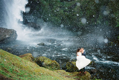 Rear view of man standing against waterfall