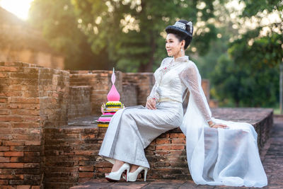 Portrait of young woman standing against wall