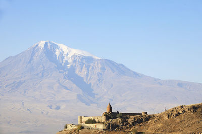 Scenic view of built structure against snowcapped mountain and sky