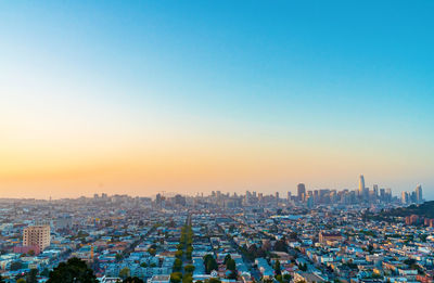 Aerial view of buildings in city against clear sky