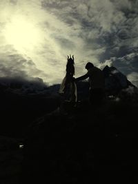 Woman standing on mountain against cloudy sky