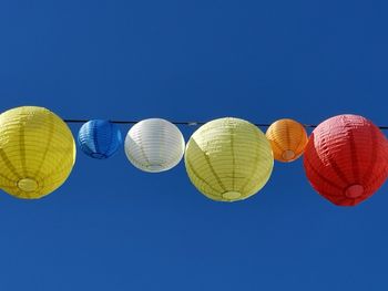 Low angle view of lanterns against clear blue sky