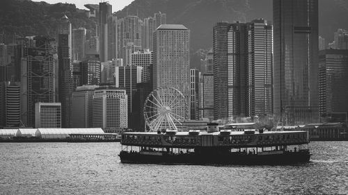 Ferry boat in sea against cityscape