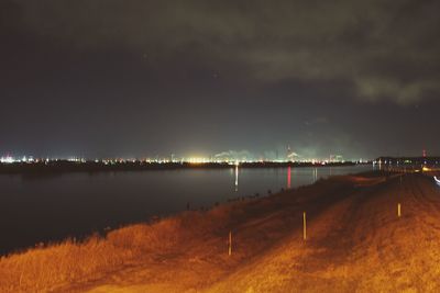 Illuminated river against sky at night