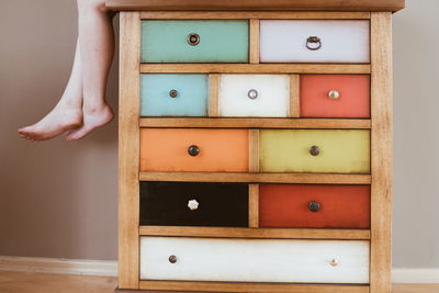 Low section of woman on cabinet at home