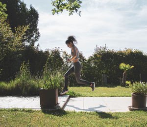 Side view of woman jumping in yard