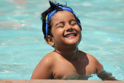 Cheerful shirtless boy swimming in pool