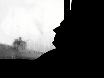 Side view of silhouette man against window