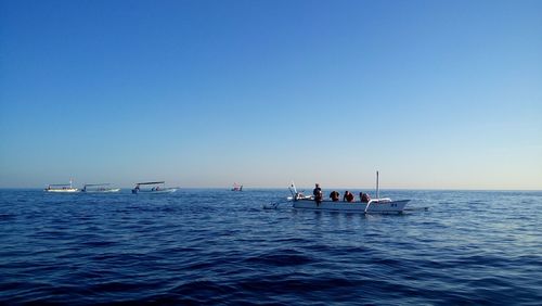 People on boat sailing in sea against clear sky