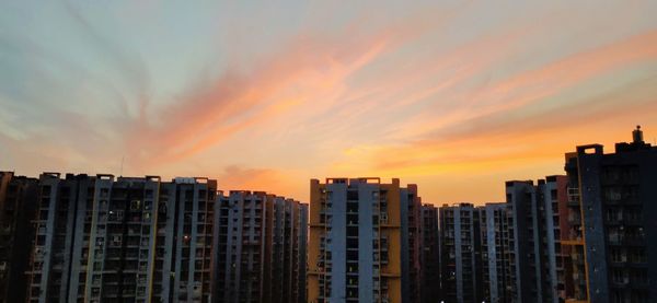 Modern buildings against sky during sunset