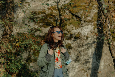 Portrait of young woman standing by tree